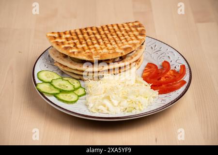 Une assiette avec des crêpes et des légumes assortis sur une table en bois Banque D'Images