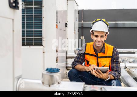 Un ingénieur assis sur le sol, parcourant une tablette en Thaïlande, Bangkok Banque D'Images