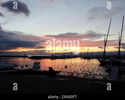 Les bateaux sur l'eau au quai pendant le coucher du soleil avec un ciel coloré Banque D'Images