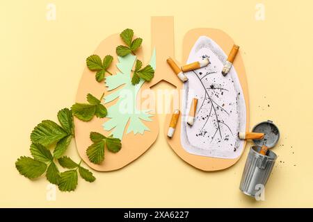 Poumons en papier avec cigarette, cendrier et feuilles vertes sur fond jaune Banque D'Images