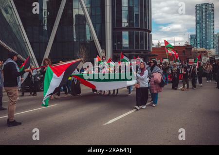 Une foule pro-palestinienne protestant dans les rues avec des drapeaux, des panneaux et des pancartes palestiniens. Banque D'Images