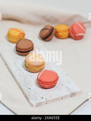 Les macarons colorés et les roses délicates disposés sur une table Banque D'Images