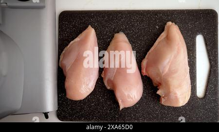 Poulet cru sans os et peau pour la cuisson. Filet de poulet sur une planche à découper. Banque D'Images