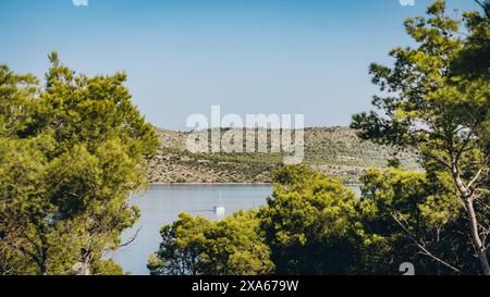 Yacht naviguant sur le lac calme le jour d'été, l'eau bleue et la forêt de conifères verdoyants dans le parc national de Telascica, Croatie Banque D'Images