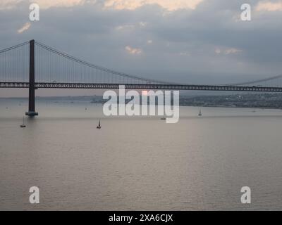 Le pont du 25 avril sur le fleuve Tejo au coucher du soleil à Lisbonne, Portugal Banque D'Images