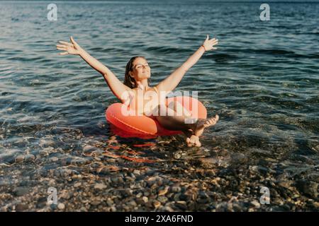 Une femme flotte dans un radeau gonflable rouge sur un plan d'eau Banque D'Images