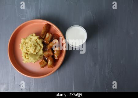 délicieux déjeuner purée de pommes de terre saucisses saucisses verre de lait sur un fond gris avec espace pour texte copyspace vue de dessus. Banque D'Images