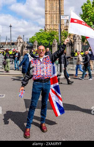 Un homme portant un costume de l'Union Jack agite une croix anglaise du drapeau de St George devant Big Ben après un rassemblement contre Two Tier Policing, Londres, Royaume-Uni. Banque D'Images