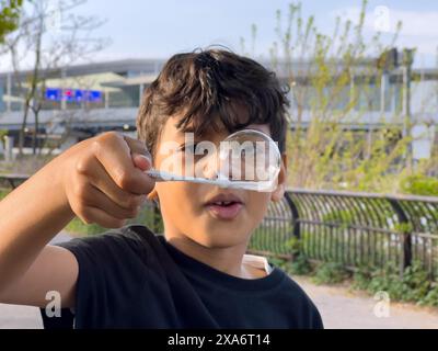 Un jeune garçon regarde à travers de grosses bulles de savon avec une brosse à dents Banque D'Images