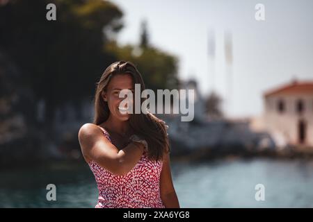 Une femme en robe rose est assise sur un bateau, souriante Banque D'Images