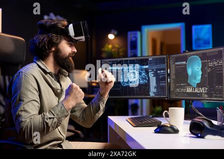 Ingénieur informatique utilisant un casque VR, célébrant après avoir éveillé l'IA sensible posant des questions existentielles. Programmeur joyeux utilisant la technologie de réalité virtuelle pour interagir avec l'intelligence artificielle Banque D'Images