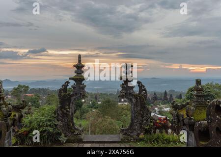 Une porte avec des lampes et de la verdure avec un ciel de coucher de soleil et des bâtiments en arrière-plan Banque D'Images