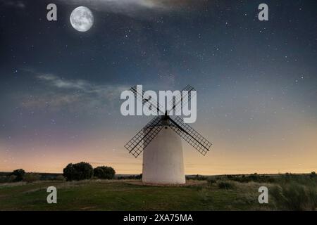 Moulin à vent au premier plan avec de grandes lames sous un ciel étoilé nocturne en arrière-plan. Banque D'Images