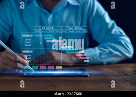 Chef de projet travaillant sur tablette et mettant à jour les tâches et jalons planification de la progression avec l'interface de planification de diagramme de Gantt pour l'entreprise sur scr virtuel Banque D'Images