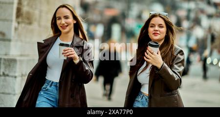 Deux belles femmes d'affaires vont travailler tout en tenant des tasses de café dans leurs mains Banque D'Images