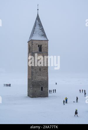 Le clocher se dresse bien en évidence dans le centre du lac Resia enneigé, entouré par un paysage hivernal serein, Haut Adige, Italie Banque D'Images