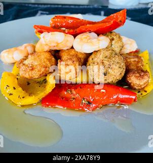 Une plaque huilyplate blanche contenant des crevettes frites, des boulettes de viande et des poivrons jaunes et rouges bien cuits Banque D'Images
