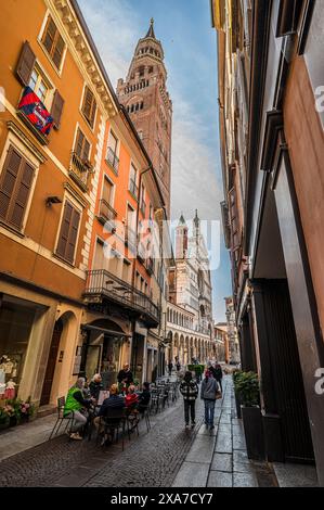 Café avec chaises dans l'allée avec clocher de la cathédrale, Crémone, province de Crémone, Lombardie, Italie, Europe Banque D'Images