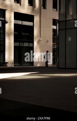 Un homme d'âge mûr debout seul près d'un bâtiment imposant sur le trottoir Banque D'Images