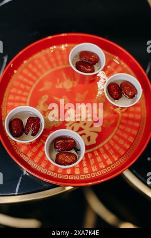 Assiette rouge avec quatre bols et dattes sur le dessus Banque D'Images