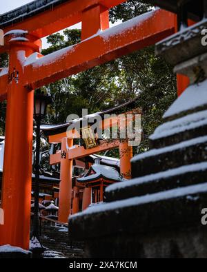 Une ancienne passerelle traditionnelle japonaise et des temples recouverts de neige rare en hiver au sanctuaire Fushimi Inari à Kyoto au Japon. Banque D'Images