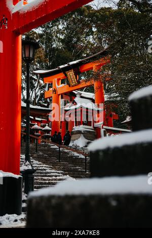 Une ancienne passerelle traditionnelle japonaise et des temples recouverts de neige rare en hiver au sanctuaire Fushimi Inari à Kyoto au Japon. Banque D'Images