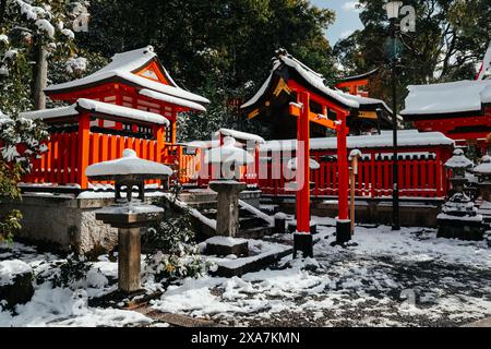 Une ancienne passerelle traditionnelle japonaise et des temples recouverts de neige rare en hiver au sanctuaire Fushimi Inari à Kyoto au Japon. Banque D'Images