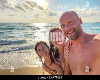 Deux femmes et un homme posant sur la plage pendant le coucher du soleil en Grèce Banque D'Images