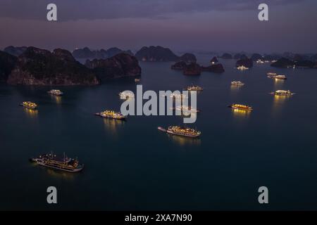 De nombreux navires éclairés près de petites îles dans des eaux calmes Banque D'Images