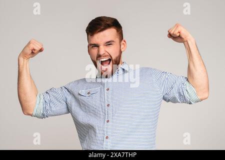 Jeune homme montrant son pouvoir dans les biceps sur camera Banque D'Images