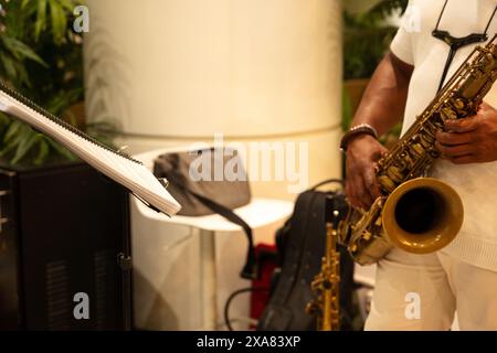 Un homme jouant du saxophone avec une feuille de musique devant lui. La musique est jazz et l'homme porte une chemise blanche Banque D'Images