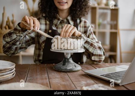 Femme sculptant de l'argile de poterie dans un atelier de céramique Banque D'Images