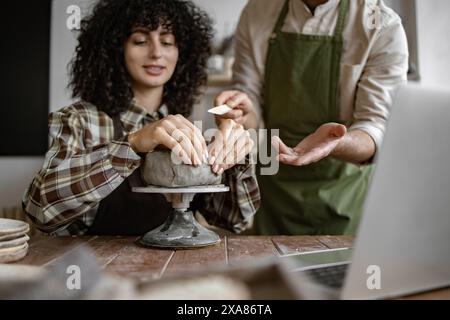 Femme apprenant la poterie avec un professeur dans un atelier de studio Banque D'Images