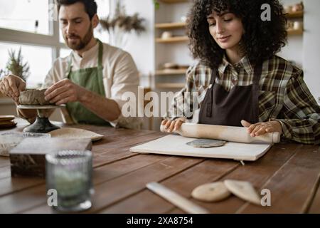 Homme mûr et femme sculptant de l'argile à l'atelier de poterie Banque D'Images