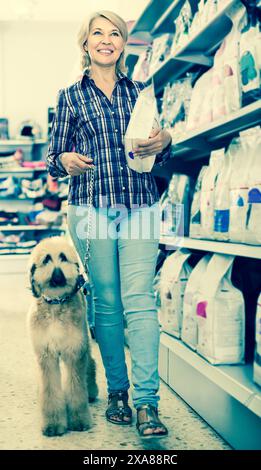 Femme achetant de la nourriture pour animaux de compagnie pour chiot berger afghan dans la boutique pour l'animal Banque D'Images