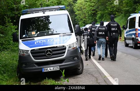 Bad Teinach Zavelstein, Allemagne. 05 juin 2024. Les policiers marchent le long d'une route devant une propriété dans une zone boisée. Un complexe immobilier et une propriété sont fouillés dans le cadre d'un raid contre des partisans présumés d'un groupe Reichsbürger. Crédit : Bernd Weißbrod/dpa/Alamy Live News Banque D'Images