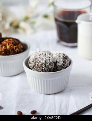 Faire des bonbons au chocolat avec des flocons de noix de coco dans un bol en céramique Banque D'Images