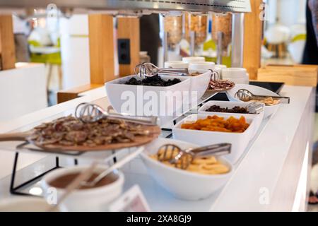 Une table de buffet avec une variété de plats, y compris des bols de fruits et de noix. La table est installée dans un restaurant ou une cafétéria Banque D'Images