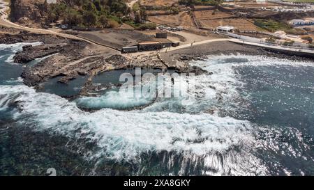 Vue aérienne des vagues se brisant contre les murs des piscines naturelles d'Agaete, une ville au nord de l'île de Gran Canaria, avec des gens enj Banque D'Images