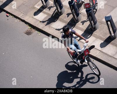 Jeune homme avec location de vélos Santander passant la station d'accueil dans le centre de Londres Banque D'Images