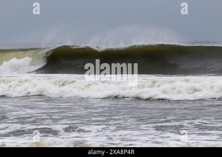 Vue horizontale d'une très grande vague formant un entonnoir alors qu'elle se brise au large de la côte de long Island. Banque D'Images