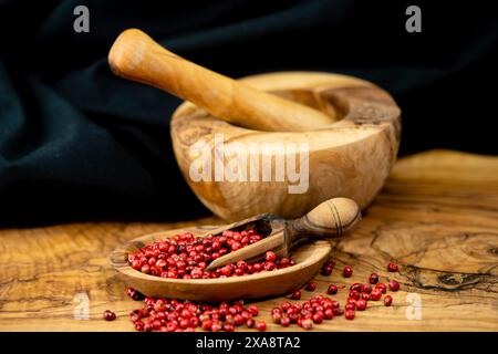 poivrier, aroeira, poivron rose, poivrier, wilelaiki, wililaiki (Schinus spec.), poivron rouge dans un Moerser et sur une pelle en bois et une assiette en bois Banque D'Images
