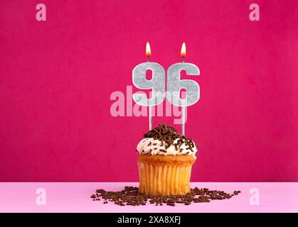 Célébration d'anniversaire avec numéro de bougie 96 - cupcake au chocolat sur fond rose Banque D'Images