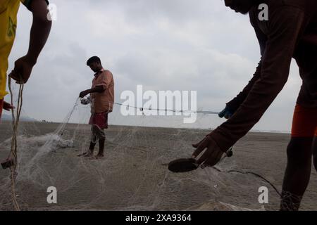 5 juin 2024, Cox's Bazar, Chittagong, Bangladesh : des pêcheurs préparent des filets de pêche pour attraper du poisson sur la plage de la mer de Cox's Bazar, Bangladesh. Le gagne-pain de la communauté des pêcheurs ici dépend largement de la pêche. Avec chaque nœud et ajustement, ils honorent une tradition intemporelle de subsistance qui s'harmonise avec les rythmes du monde naturel. Cox's Bazar, la plus longue plage marine naturelle du monde, s'étend sur plus de 120 kilomètres le long de la côte sud-est du Bangladesh. Réputée pour son sable doré, ses couchers de soleil vibrants et ses vagues, elle attire des millions de touristes chaque année. (Crédit image : © Joy Banque D'Images