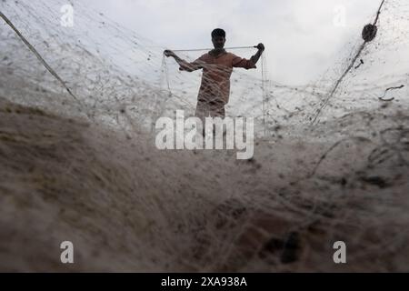 5 juin 2024, Cox's Bazar, Chittagong, Bangladesh : des pêcheurs préparent des filets de pêche pour attraper du poisson sur la plage de la mer de Cox's Bazar, Bangladesh. Le gagne-pain de la communauté des pêcheurs ici dépend largement de la pêche. Avec chaque nœud et ajustement, ils honorent une tradition intemporelle de subsistance qui s'harmonise avec les rythmes du monde naturel. Cox's Bazar, la plus longue plage marine naturelle du monde, s'étend sur plus de 120 kilomètres le long de la côte sud-est du Bangladesh. Réputée pour son sable doré, ses couchers de soleil vibrants et ses vagues, elle attire des millions de touristes chaque année. (Crédit image : © Joy Banque D'Images
