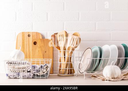 Un ensemble de plaques en céramique dans le séchoir, des outils de cuisine en bois, des planches à découper, de nombreuses serviettes différentes dans la zone de stockage. Style éco à la mode dans la cuisine. Banque D'Images