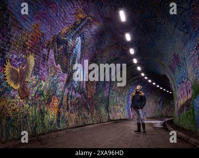 Édimbourg, Écosse, Royaume-Uni ; 01-21-2020 : vue de l'ancien tunnel ferroviaire de Colinton, décoré de graffitis illustrant un poème, avec un jeune homme regardant Banque D'Images