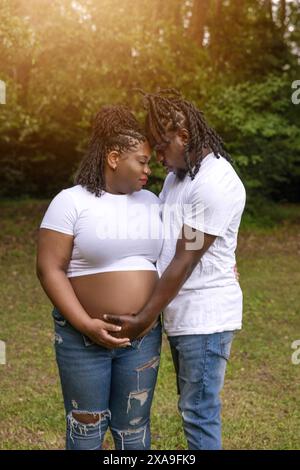 Objectif Flare avec un beau couple afro-américain posant pour des portraits de maternité alors qu'ils attendent un nouveau bébé Banque D'Images