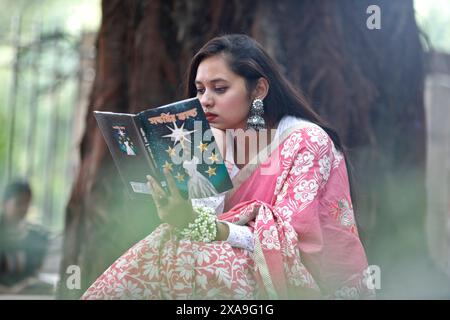 Dhaka, Bangladesh - 23 mai 2024 : un étudiant lisant un livre assis dans une bibliothèque ouverte dans la zone de l'Université de Dhaka, Dhaka, Bangladesh. Banque D'Images