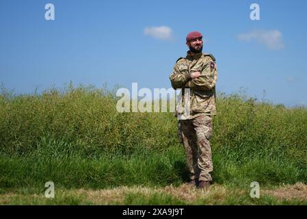 Le capitaine Maik Biggs, du 16e Régiment médical, dont le grand-père a combattu pour les nazis pendant la seconde Guerre mondiale, pose après avoir participé à un saut en parachute aux côtés de membres des forces armées britanniques, belges, canadiennes et américaines, organisé par la Royal Air Force et l'armée britannique au-dessus de la zone de dépôt K, près de Sannerville, en France, pour commémorer le rôle des forces aéroportées lors du débarquement en Normandie, à l'approche du 80e anniversaire du jour J. Date de la photo : mercredi 5 juin 2024. Banque D'Images